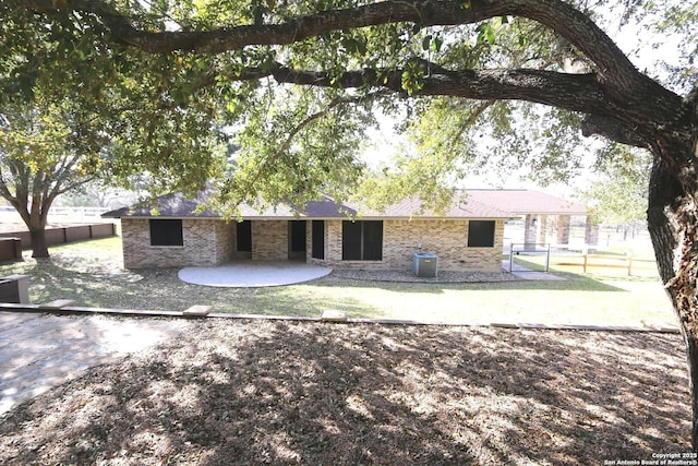 rear view of property with brick siding, a patio, central AC unit, and fence