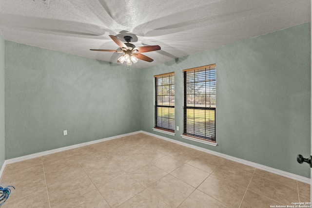 tiled spare room with a textured ceiling, baseboards, and a ceiling fan