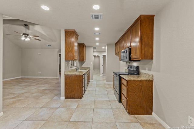 1300 Windmill Dr, La Vernia, TX 78121 - kitchen with electric range, brown cabinets, stainless steel microwave, and visible vents