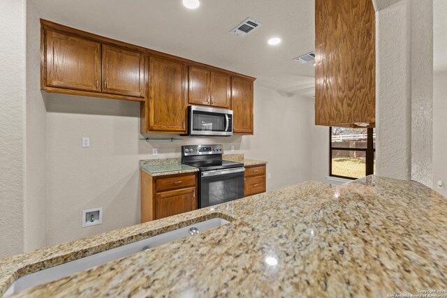 1300 Windmill Dr, La Vernia, TX 78121 - kitchen with stainless steel appliances, light stone countertops, and visible vents
