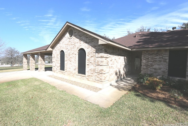 view of property exterior featuring brick siding, a yard, and roof with shingles