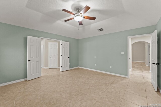 1300 Windmill Dr, La Vernia, TX 78121 - unfurnished bedroom with a tray ceiling, arched walkways, visible vents, and baseboards