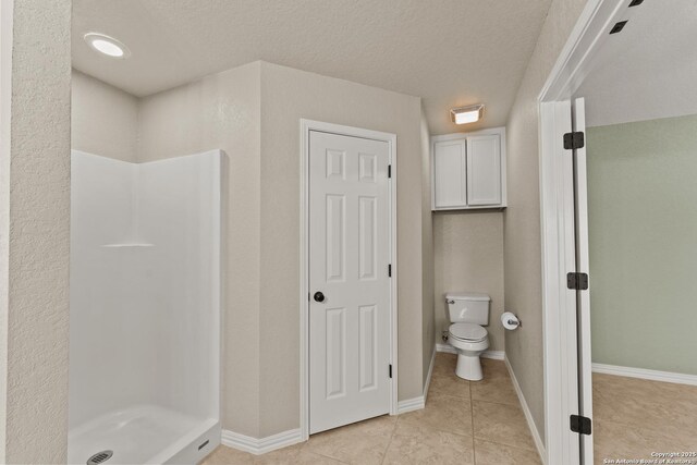 1300 Windmill Dr, La Vernia, TX 78121 - bathroom with toilet, a stall shower, a textured ceiling, tile patterned flooring, and baseboards