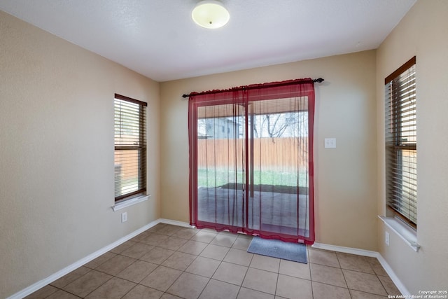 unfurnished room with light tile patterned floors, baseboards, and a healthy amount of sunlight