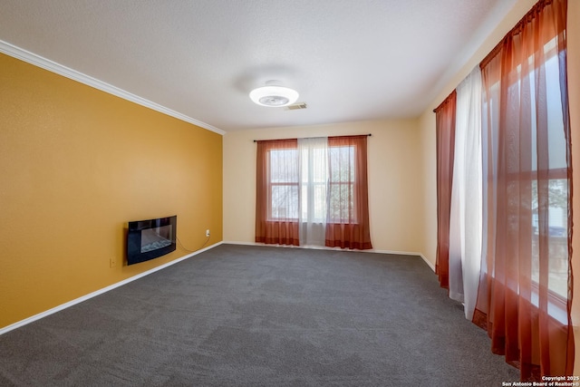 unfurnished room featuring baseboards, visible vents, dark carpet, and crown molding