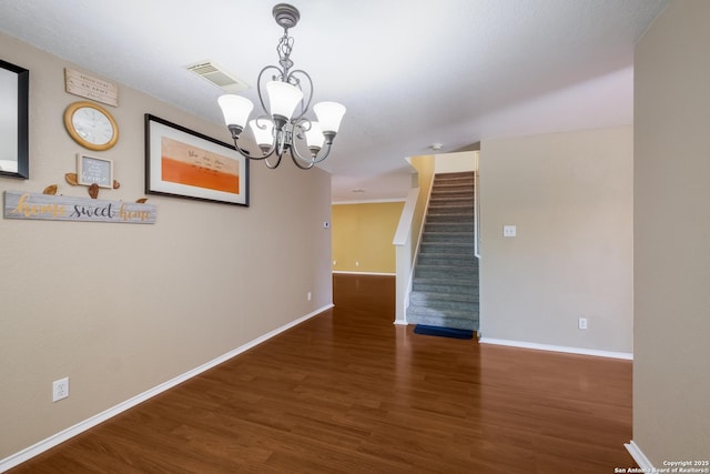 unfurnished room with stairs, baseboards, wood finished floors, and a notable chandelier