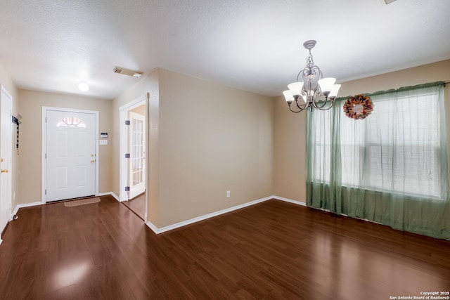 foyer with visible vents, a textured ceiling, wood finished floors, a chandelier, and baseboards