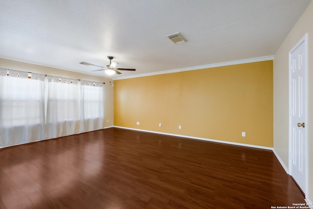 empty room with crown molding, wood finished floors, visible vents, and baseboards