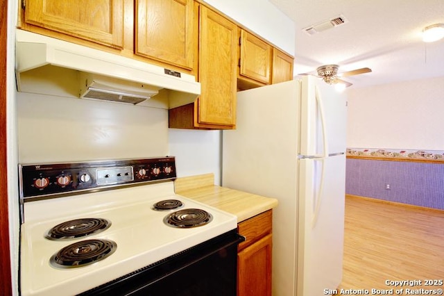 kitchen with visible vents, range with electric cooktop, freestanding refrigerator, light countertops, and under cabinet range hood