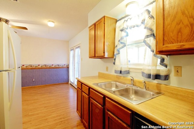 kitchen with light countertops, a sink, freestanding refrigerator, and a healthy amount of sunlight