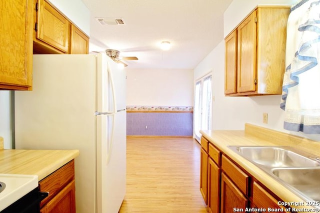 kitchen with a sink, visible vents, a ceiling fan, light countertops, and freestanding refrigerator