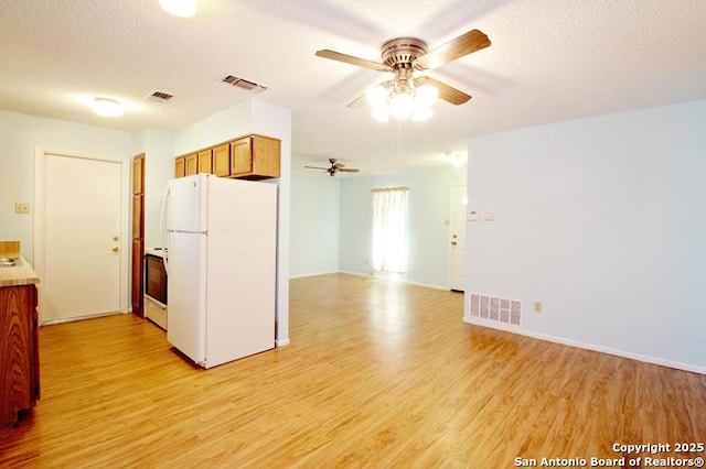 kitchen featuring light wood-style flooring, visible vents, and freestanding refrigerator