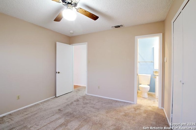 unfurnished bedroom with a textured ceiling, ensuite bathroom, carpet flooring, visible vents, and baseboards