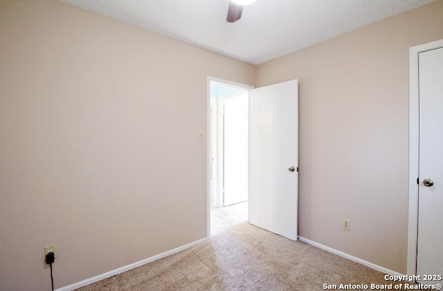 empty room featuring carpet floors, ceiling fan, a textured ceiling, and baseboards