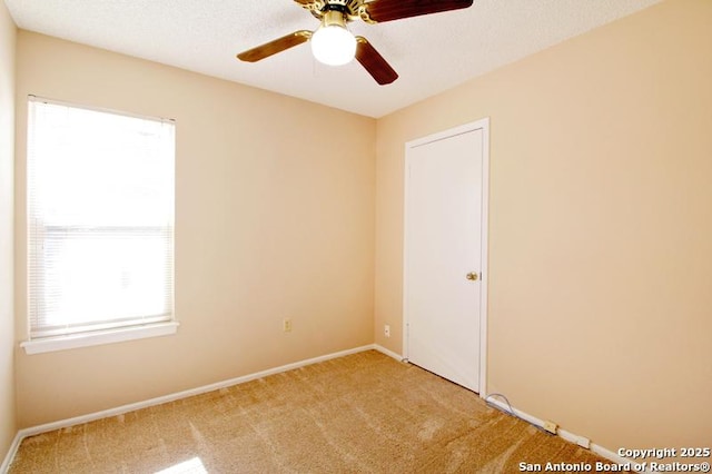 spare room featuring a ceiling fan, light carpet, a textured ceiling, and baseboards