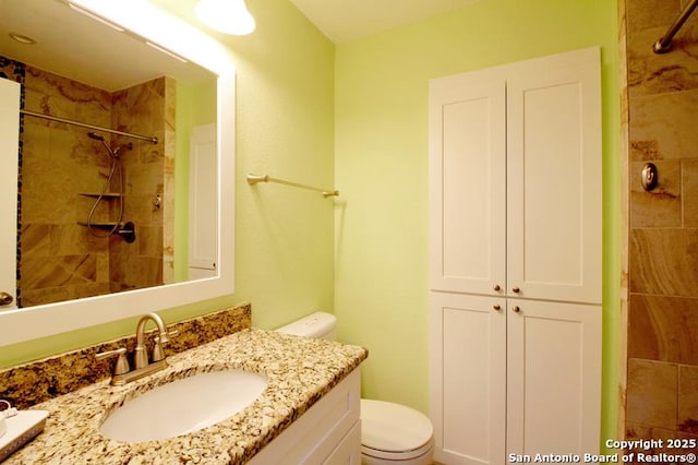 full bath with a tile shower, vanity, and toilet