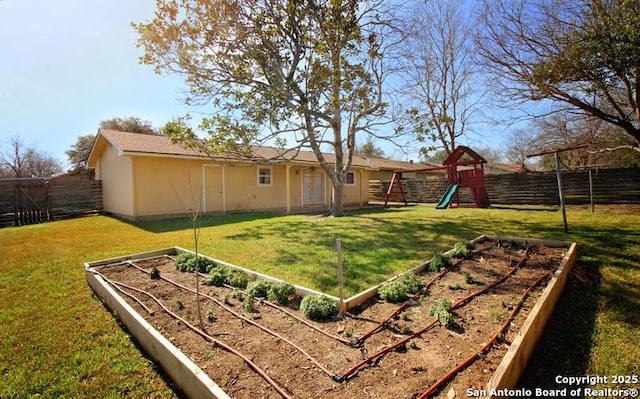 view of yard featuring a garden, a playground, and a fenced backyard