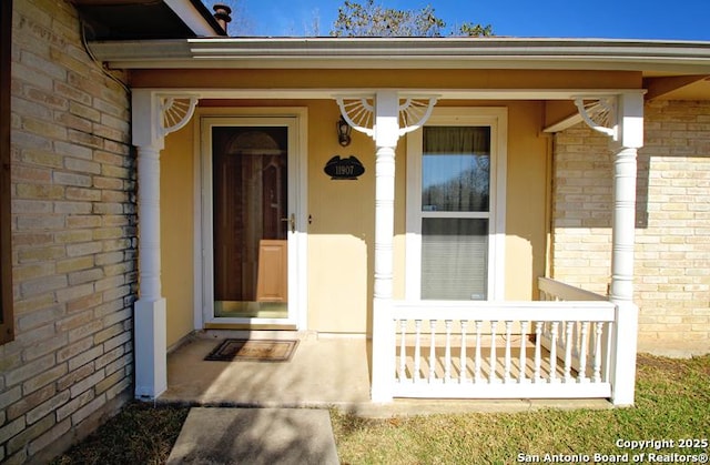 doorway to property featuring brick siding and a porch