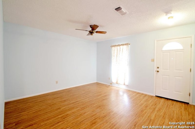 foyer entrance featuring visible vents, light wood-style floors, a ceiling fan, a textured ceiling, and baseboards