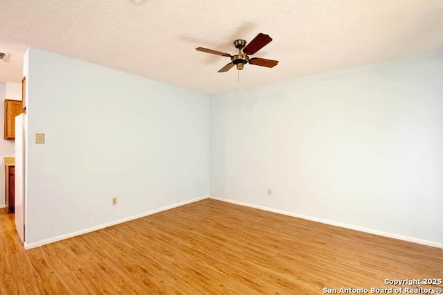 unfurnished room with ceiling fan, light wood-style flooring, and a textured ceiling