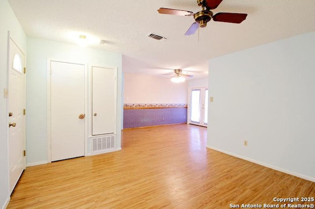 empty room featuring light wood-type flooring, visible vents, and a textured ceiling