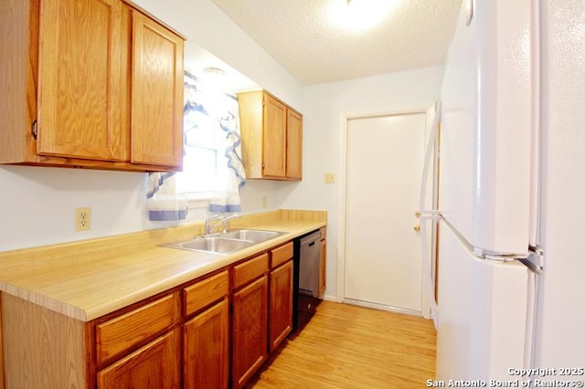 kitchen with a textured ceiling, a sink, light countertops, freestanding refrigerator, and dishwasher