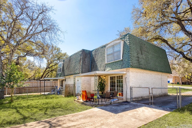 back of property featuring a patio, mansard roof, brick siding, fence, and a gate