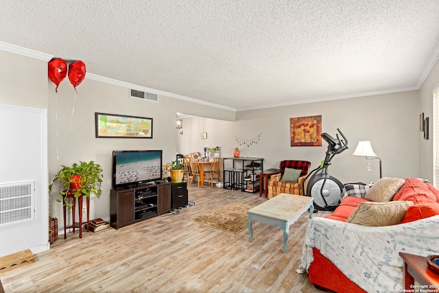 living area with visible vents, crown molding, and wood finished floors