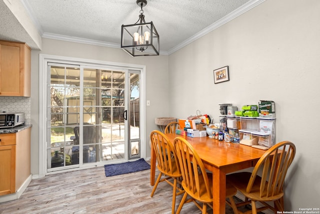 dining room featuring a notable chandelier, a textured ceiling, light wood-type flooring, and crown molding