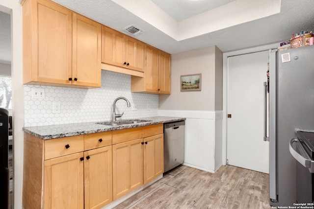 kitchen featuring a sink, visible vents, light wood-style floors, appliances with stainless steel finishes, and light stone countertops