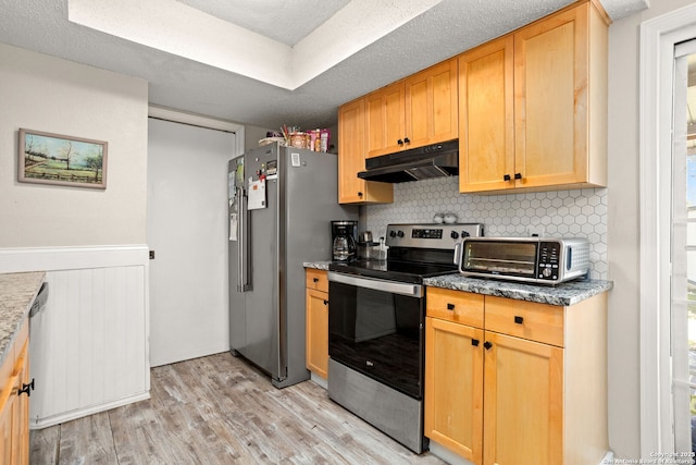 kitchen with a toaster, stainless steel appliances, decorative backsplash, light wood-style floors, and under cabinet range hood