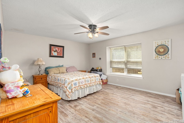 bedroom featuring baseboards, ceiling fan, light wood-style flooring, and a textured ceiling