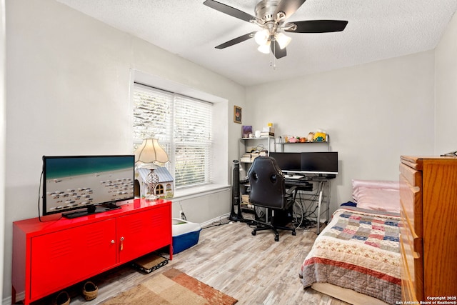 bedroom with ceiling fan, a textured ceiling, and wood finished floors