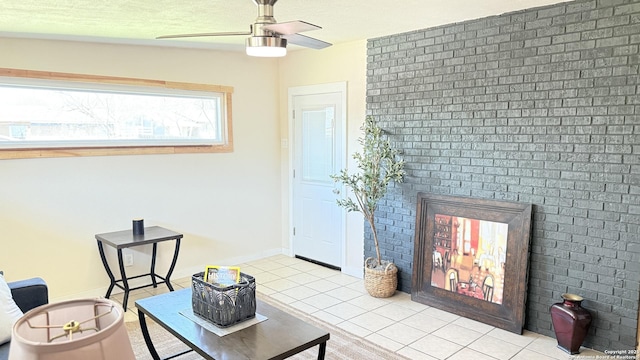 sitting room with light tile patterned floors, ceiling fan, a fireplace, and baseboards