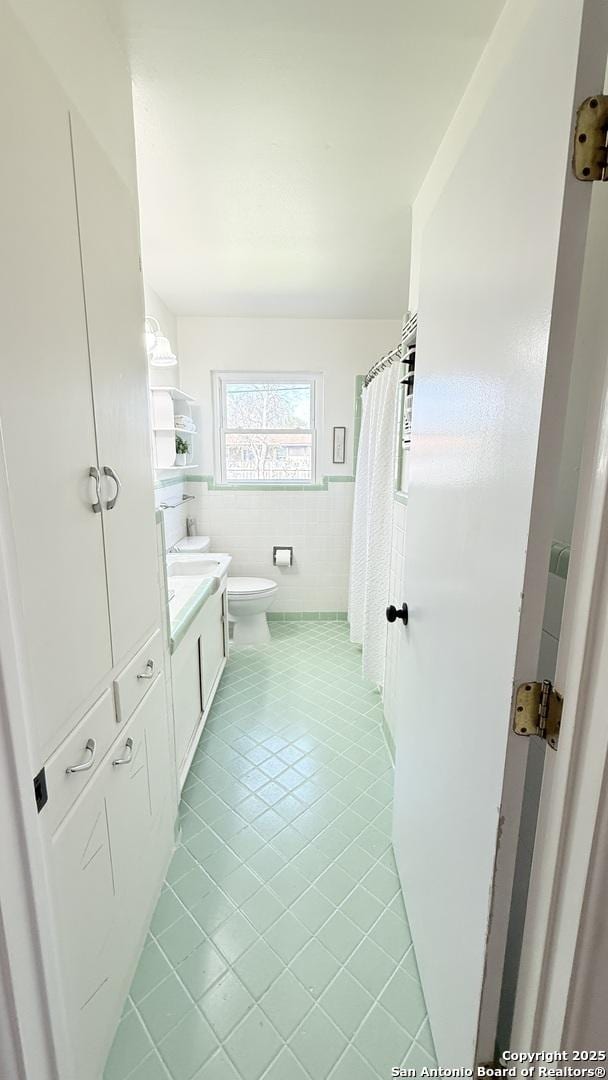 bathroom featuring tile walls, toilet, wainscoting, vanity, and tile patterned flooring