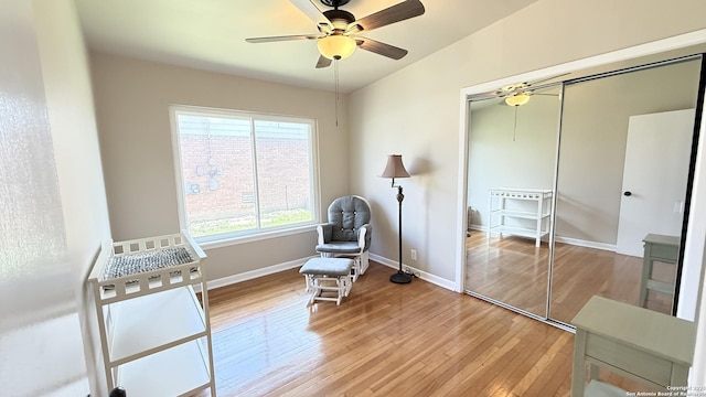 living area featuring a ceiling fan, baseboards, and hardwood / wood-style flooring