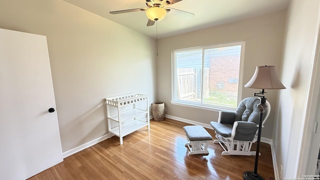 sitting room with a ceiling fan, baseboards, and wood finished floors