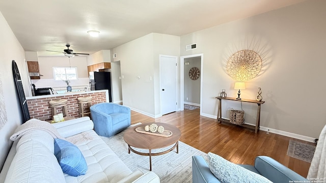 living room with visible vents, ceiling fan, baseboards, and wood finished floors