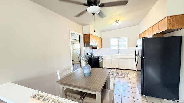 kitchen with light tile patterned floors, freestanding refrigerator, stainless steel gas range, light countertops, and a sink