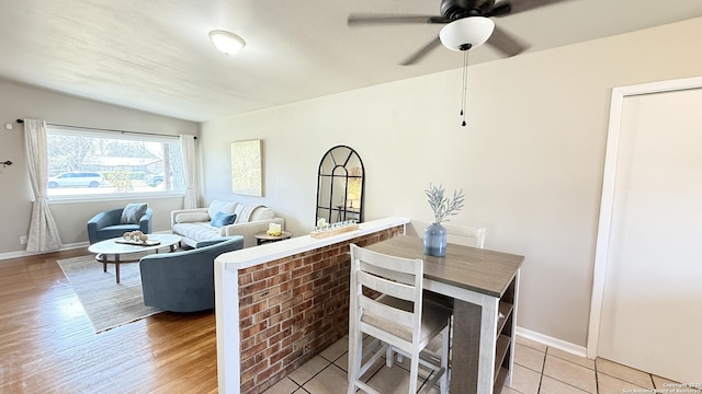 dining space featuring a ceiling fan, light wood-type flooring, and baseboards