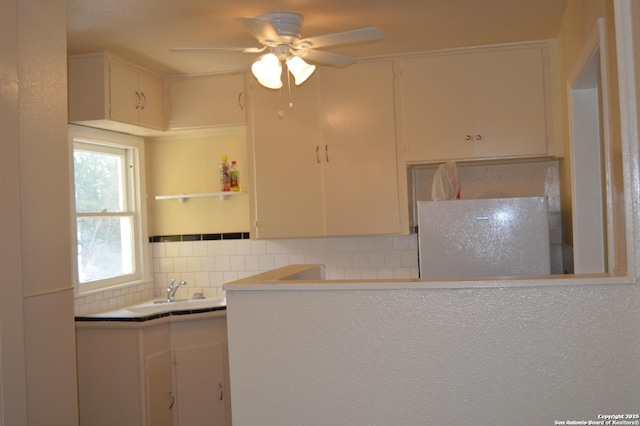 kitchen with tasteful backsplash, white cabinetry, light countertops, and a ceiling fan