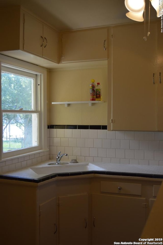 kitchen with tile counters, a sink, and decorative backsplash