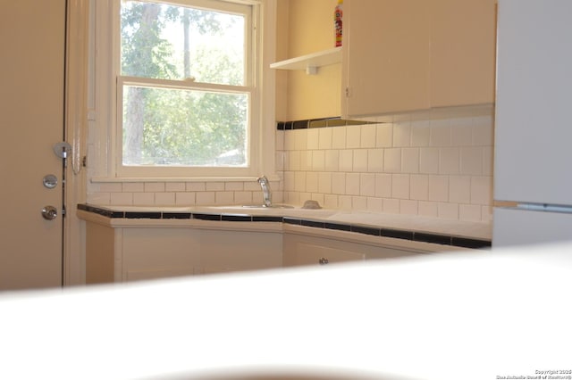 kitchen with tile countertops, open shelves, tasteful backsplash, freestanding refrigerator, and white cabinetry