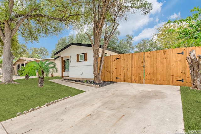 view of front of property with brick siding, a gate, fence, and a front yard