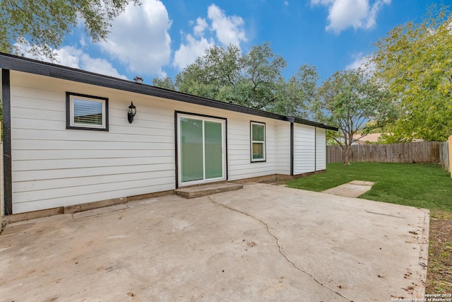 back of property with a yard, a patio, and fence