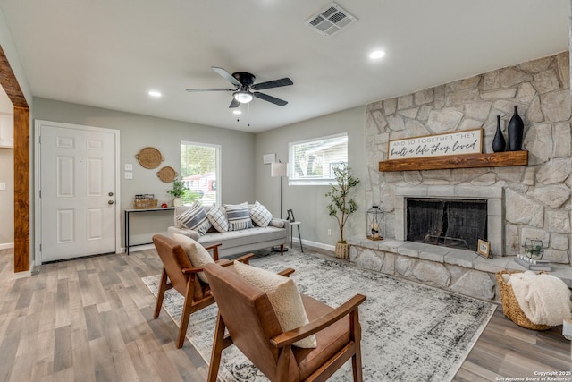 living area featuring visible vents, baseboards, ceiling fan, light wood-type flooring, and a fireplace