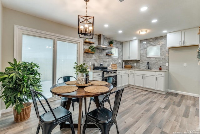 kitchen with tasteful backsplash, electric range, light wood-style floors, white cabinetry, and a sink