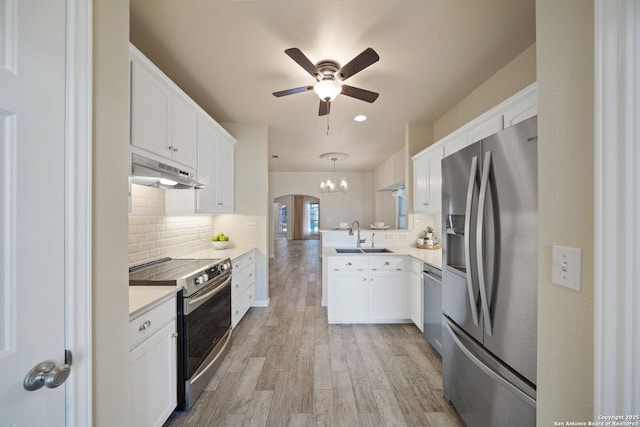 kitchen featuring a peninsula, light wood-style flooring, a sink, stainless steel appliances, and under cabinet range hood