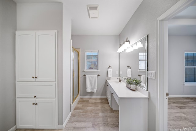 full bath with a stall shower, vanity, baseboards, and wood finished floors