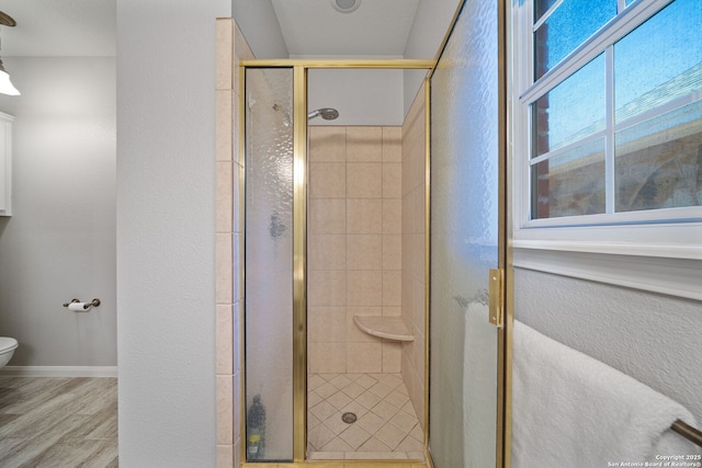 full bathroom featuring toilet, wood finished floors, a stall shower, and baseboards